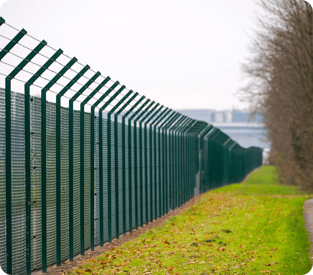 Tall metal fence beside grassy path.